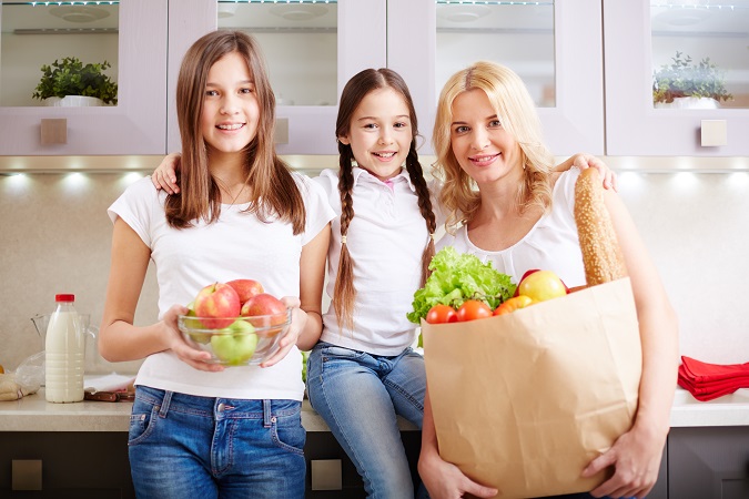 happy mother and two daughters looking at camera in the kitchen